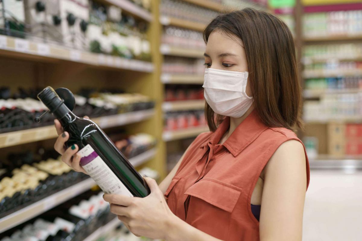 Consumatrice che sceglie una bottiglia di vino durante la pandemia